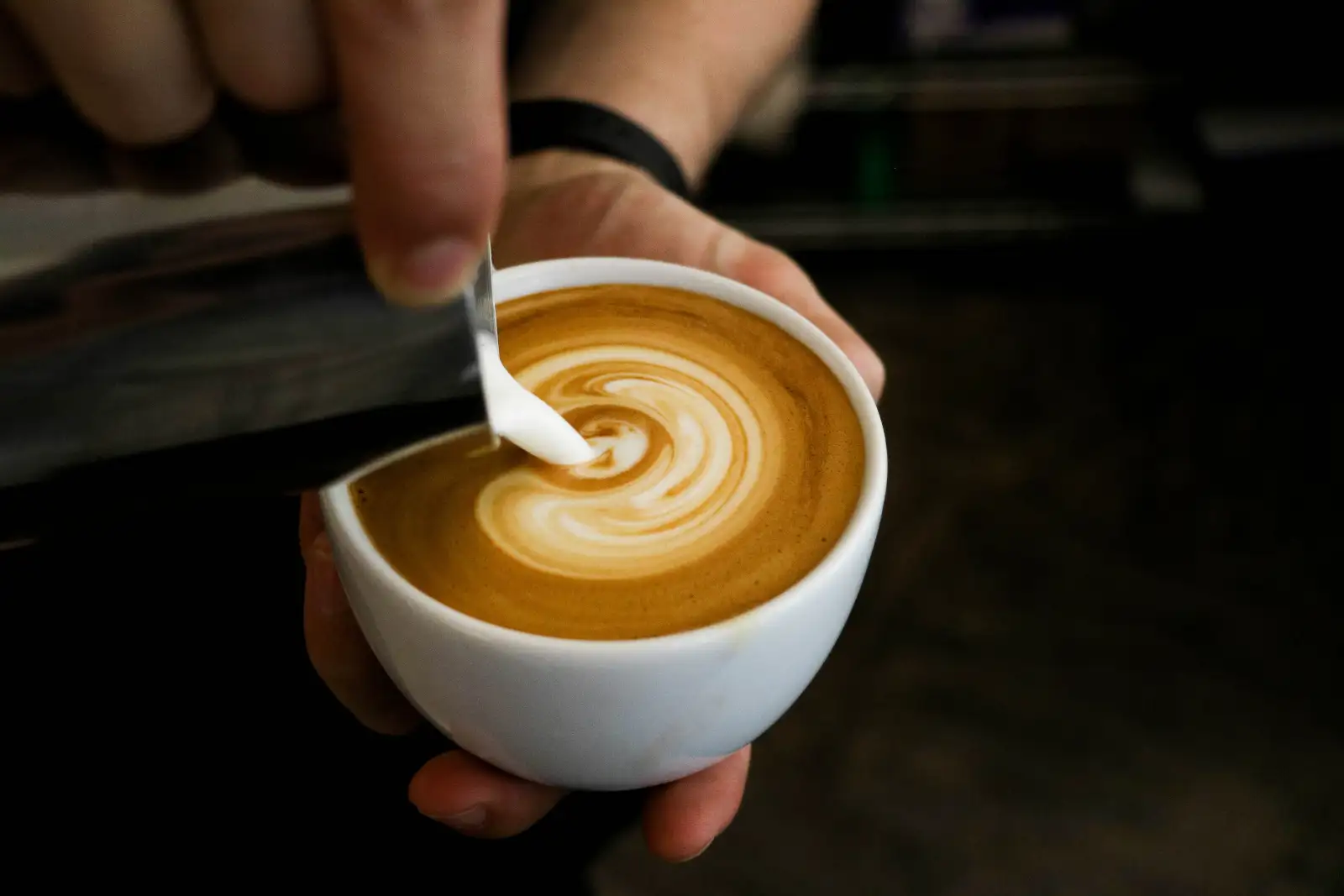Steamed milk being poured into a cup of espresso